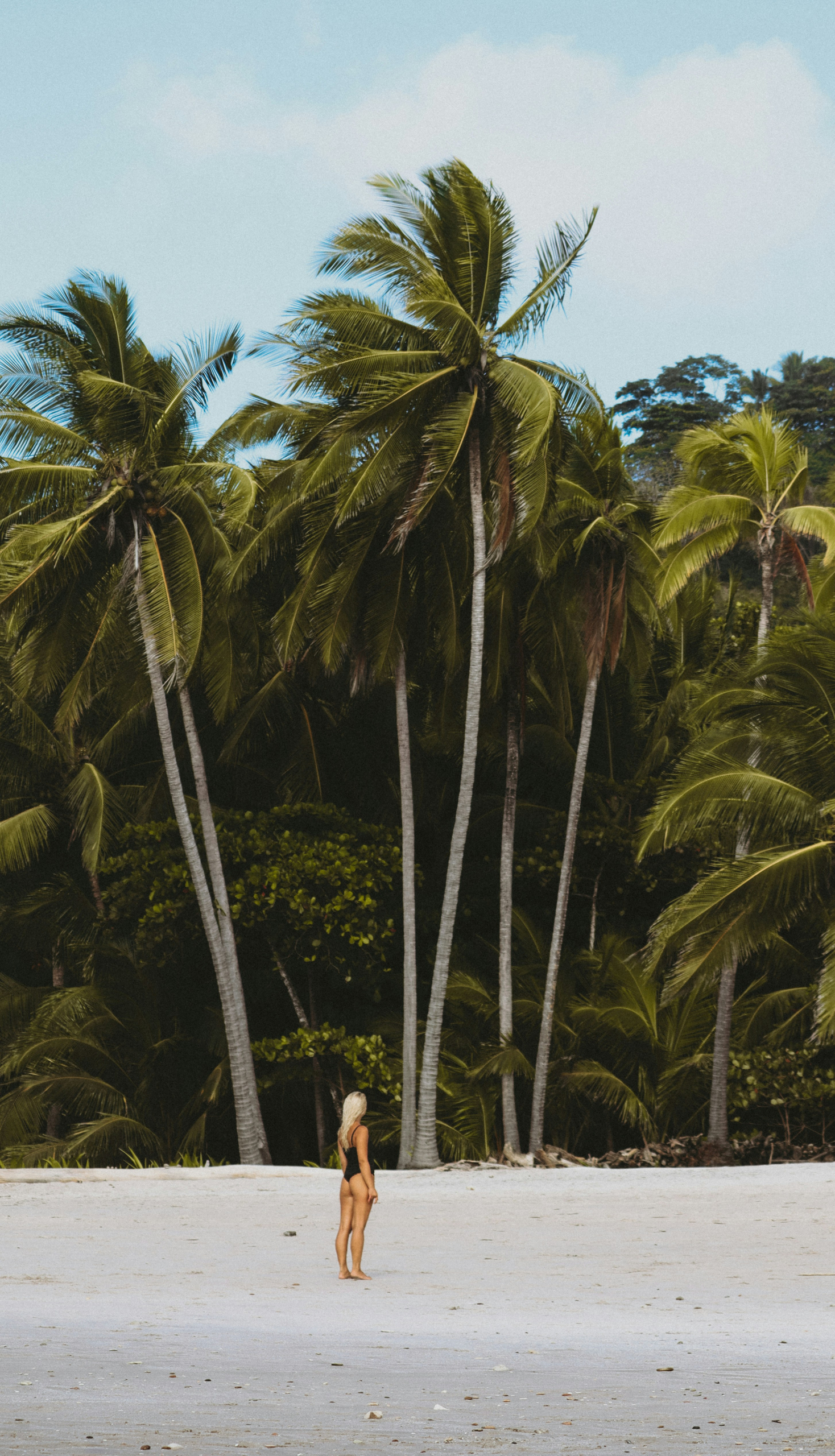 A woman standing alone on a Costa Rica beach — the kind of location where advance positioning makes the difference between effective coverage and a missed window